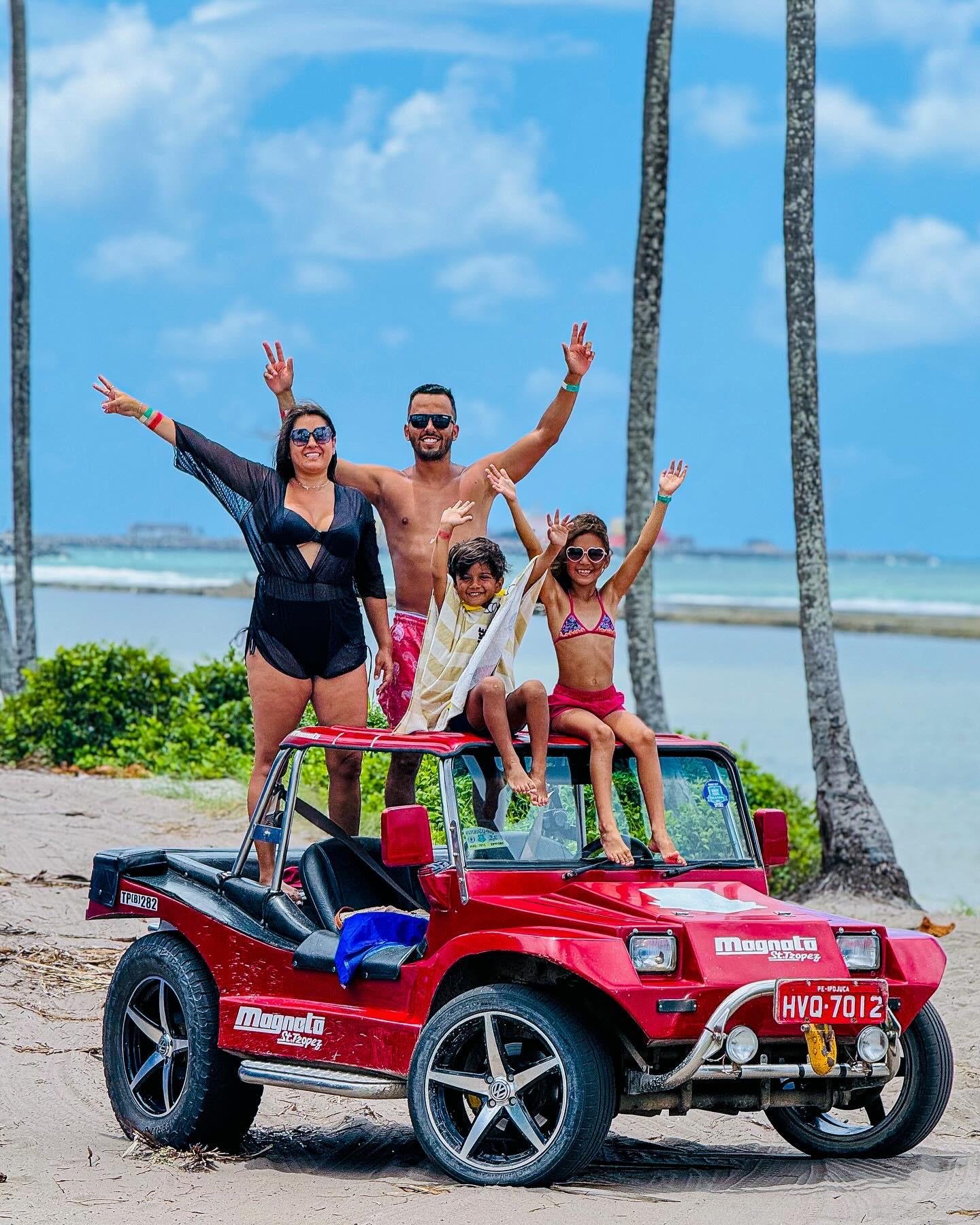 Uma familia de 4 pessoas em cima de um buggy vermelho